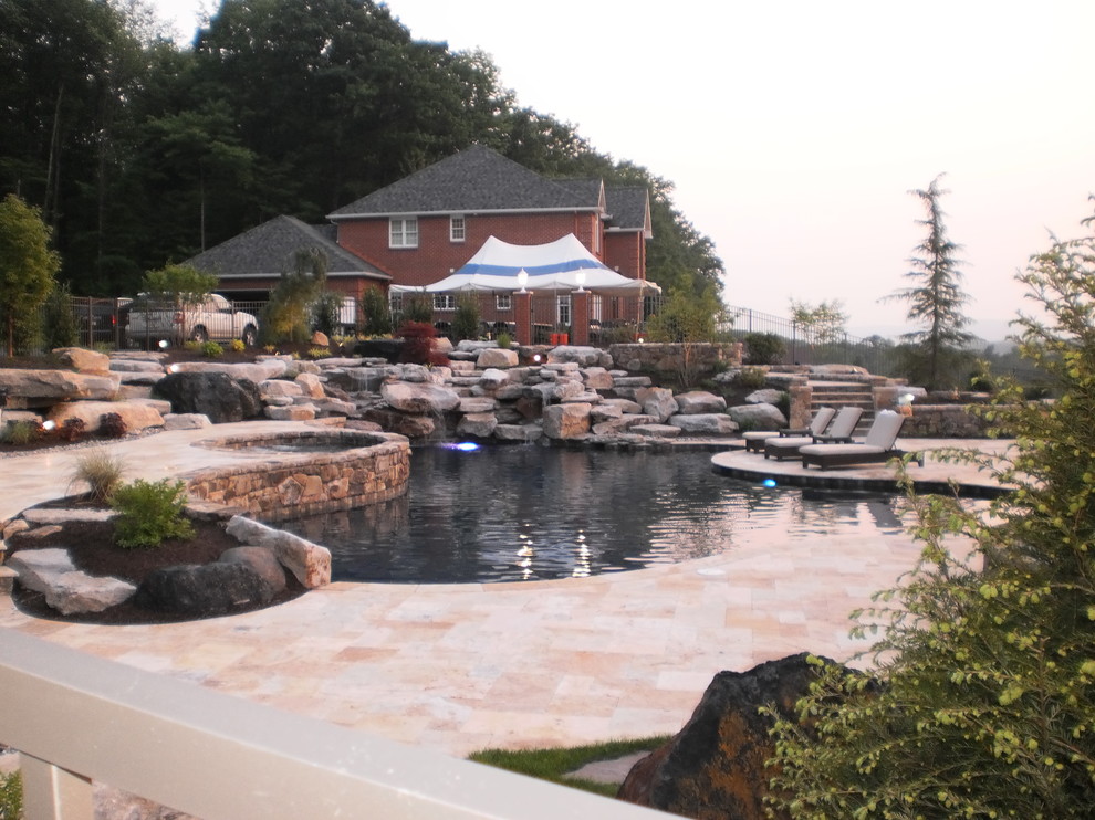 Immagine di una grande piscina naturale classica personalizzata dietro casa con fontane e pavimentazioni in pietra naturale