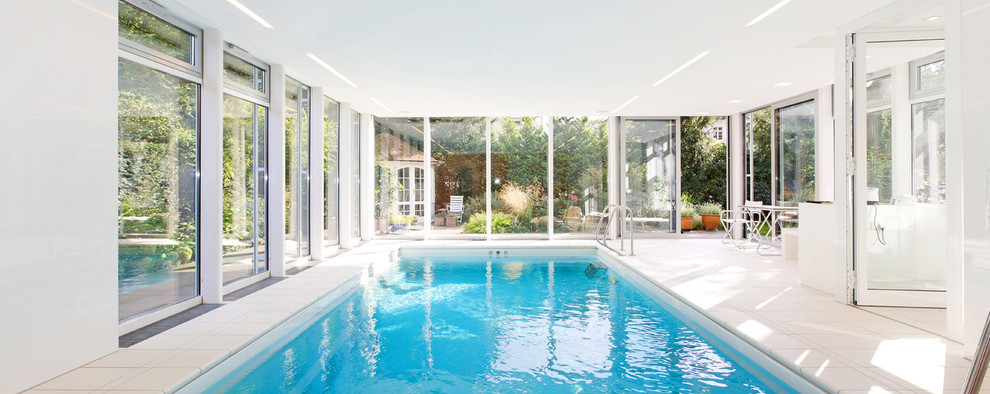 Modelo de casa de la piscina y piscina contemporánea grande rectangular y interior con suelo de baldosas
