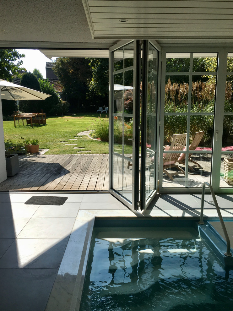 Ejemplo de casa de la piscina y piscina elevada campestre de tamaño medio interior y rectangular con losas de hormigón