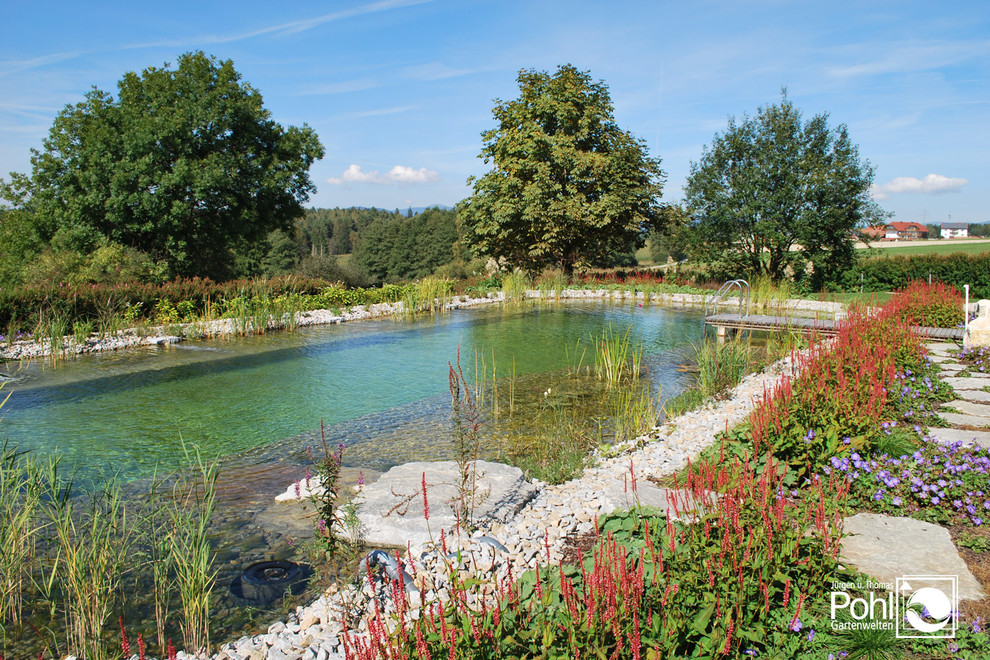 Aménagement d'une grande piscine naturelle contemporaine sur mesure avec du gravier.