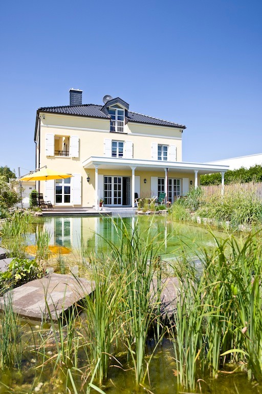 Immagine di una grande piscina naturale contemporanea personalizzata dietro casa con fontane e pavimentazioni in pietra naturale