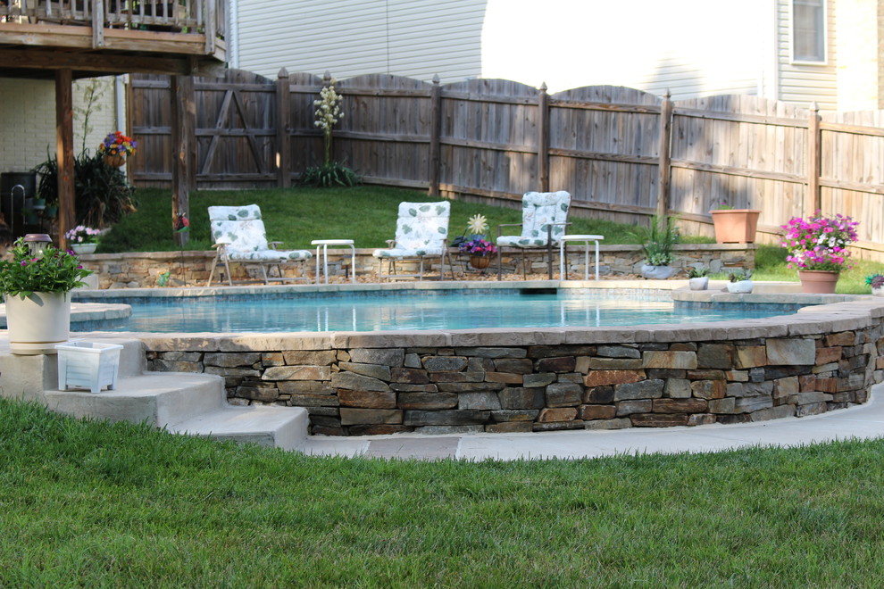 Immagine di una piscina naturale stile rurale personalizzata di medie dimensioni e dietro casa con lastre di cemento