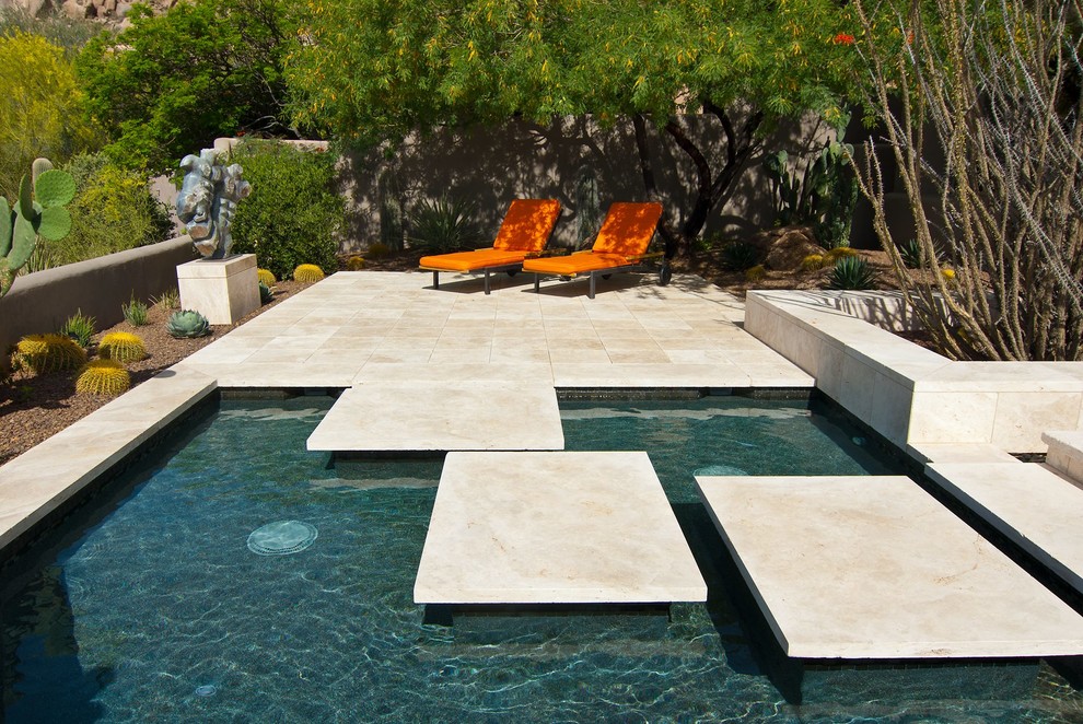 Large modern back rectangular lengths swimming pool in Phoenix with natural stone paving.