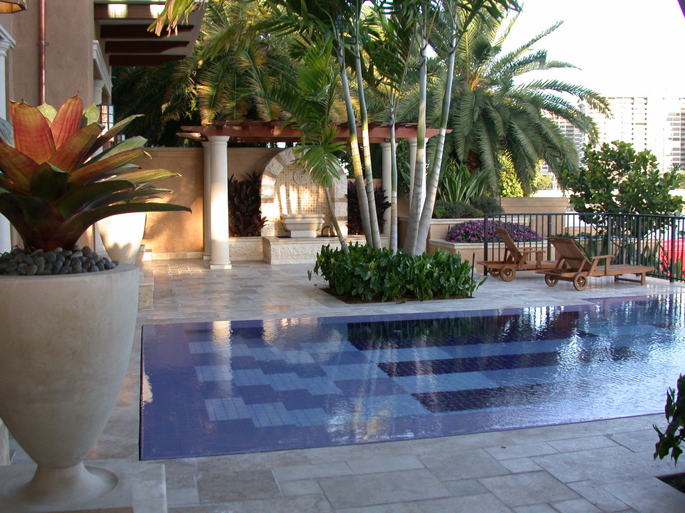 Esempio di una piscina tropicale rettangolare con pavimentazioni in pietra naturale