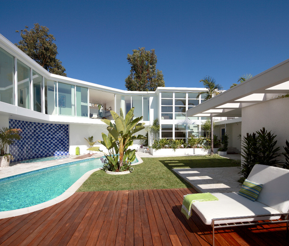 Inspiration for a mid-sized contemporary backyard custom-shaped pool house remodel in Los Angeles with decking