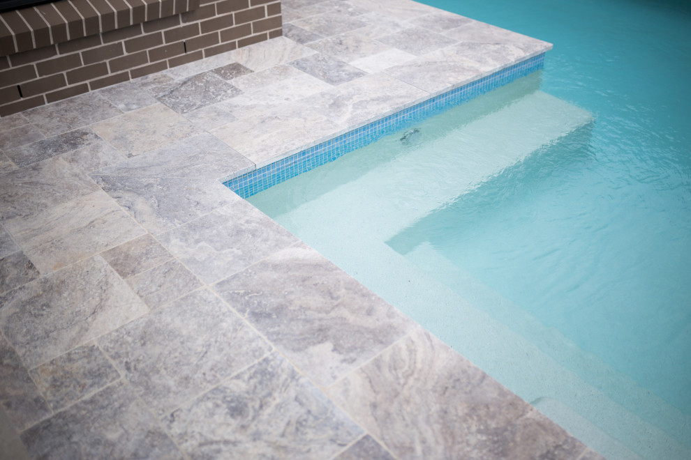 Cette image montre une grande piscine naturelle et arrière design en L avec des pavés en pierre naturelle.