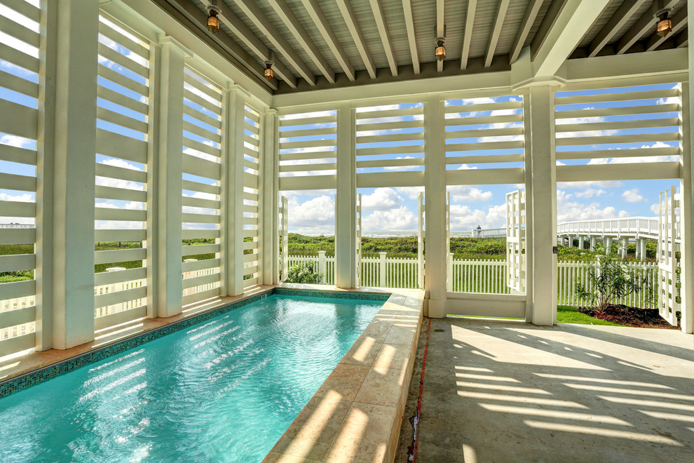 This is an example of a beach style indoor rectangular lengths swimming pool in Houston with a pool house and concrete slabs.