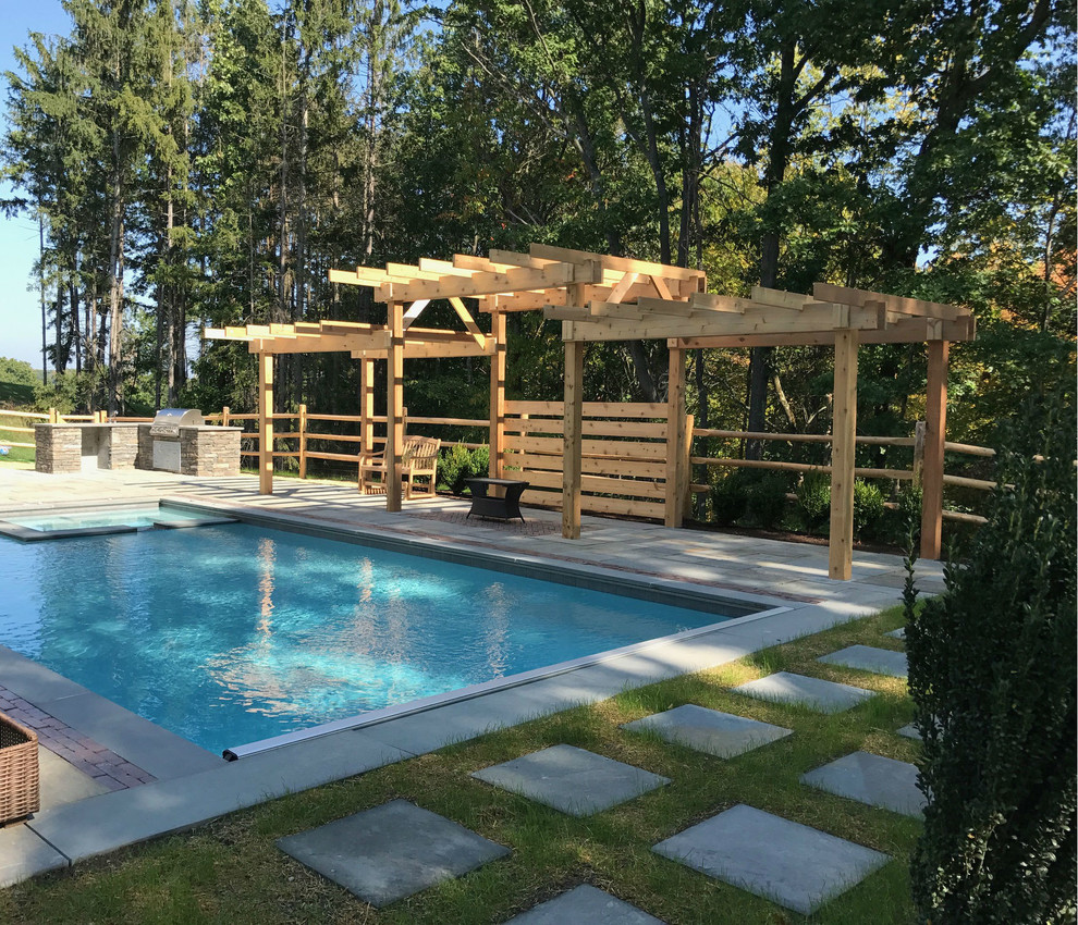 Immagine di una piscina naturale contemporanea rettangolare dietro casa con paesaggistica bordo piscina e pavimentazioni in pietra naturale