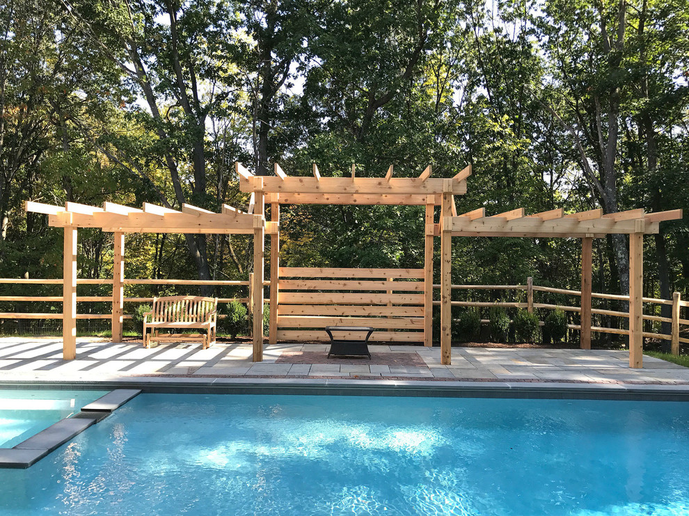 This is an example of a contemporary back rectangular natural swimming pool in New York with with pool landscaping and natural stone paving.