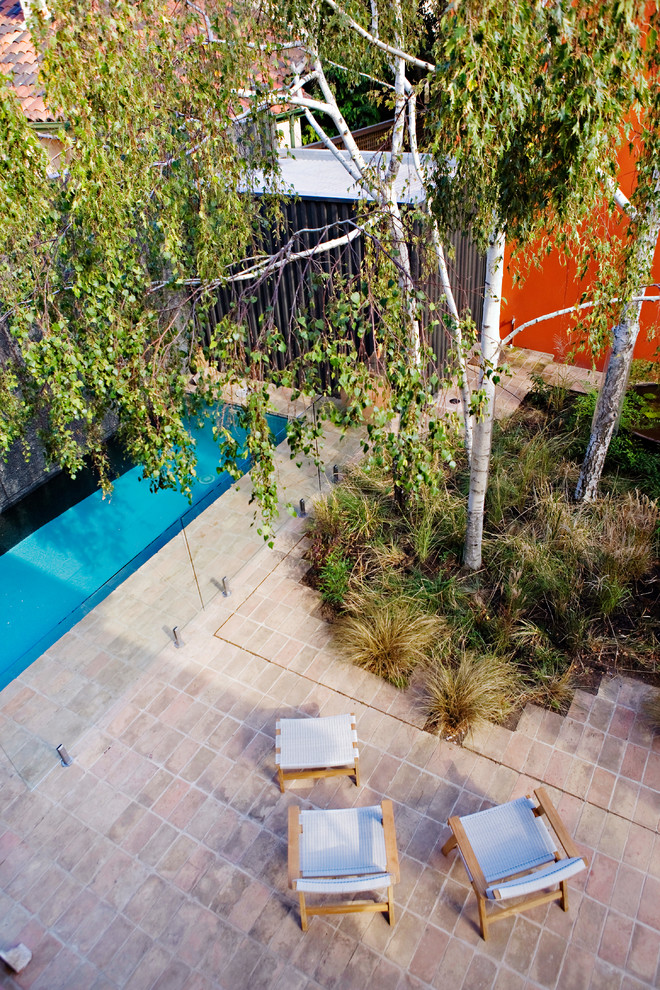 Esempio di una piccola piscina monocorsia minimal rettangolare dietro casa con pavimentazioni in pietra naturale