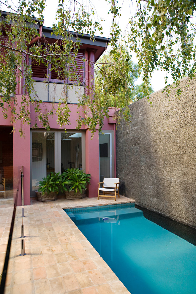 Foto de piscina alargada actual pequeña rectangular en patio trasero con adoquines de piedra natural