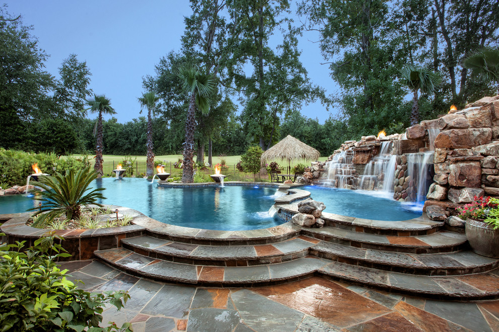 Idée de décoration pour une très grande piscine à débordement et arrière ethnique sur mesure avec des pavés en pierre naturelle et un bain bouillonnant.