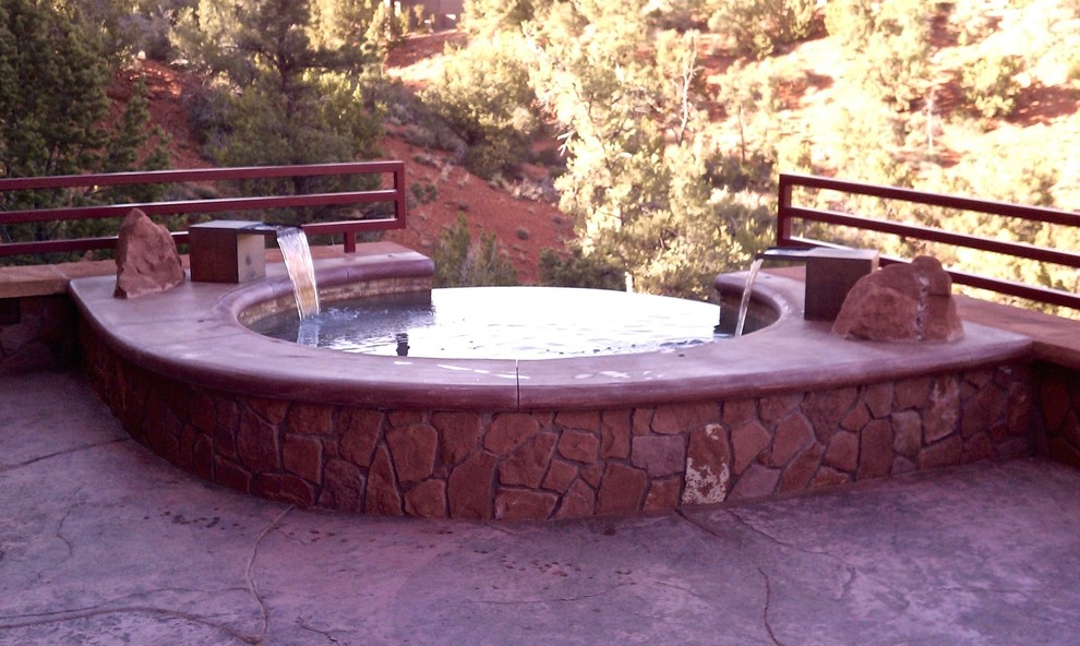 Modelo de piscina con fuente infinita tradicional pequeña redondeada en patio trasero con adoquines de piedra natural