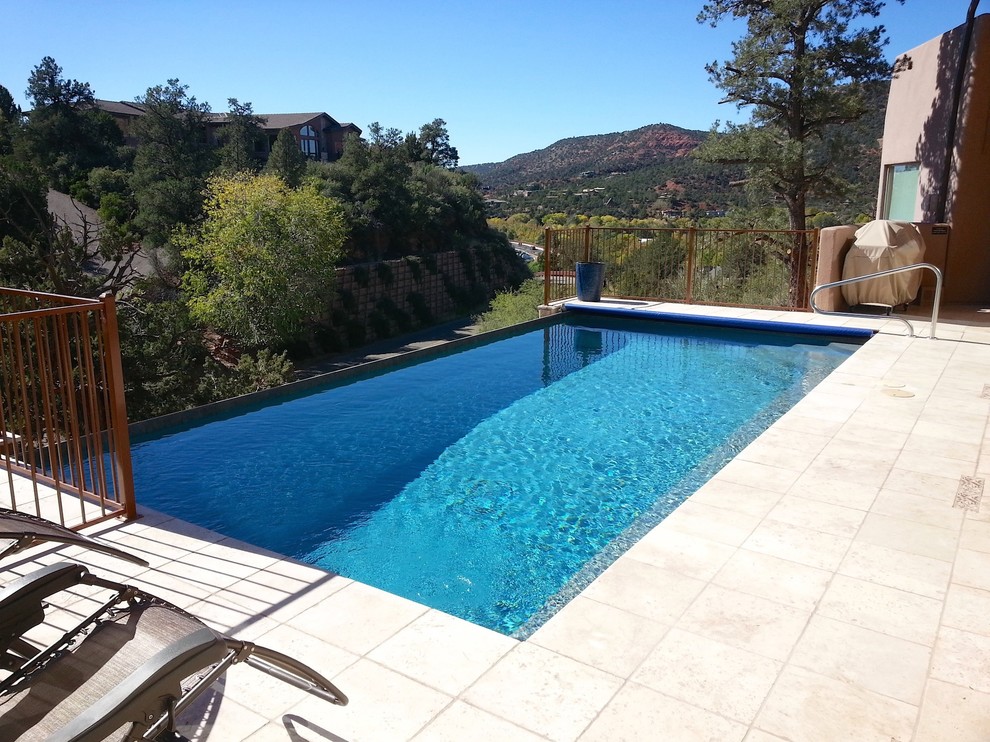 Foto di una grande piscina a sfioro infinito minimal rettangolare dietro casa con fontane e piastrelle