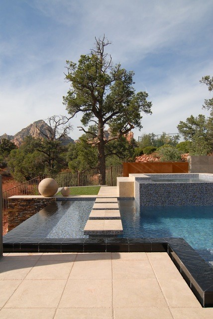 Ejemplo de piscina con fuente infinita moderna a medida en patio trasero con entablado