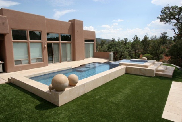 Cette photo montre une piscine à débordement et arrière tendance rectangle avec un point d'eau et une terrasse en bois.