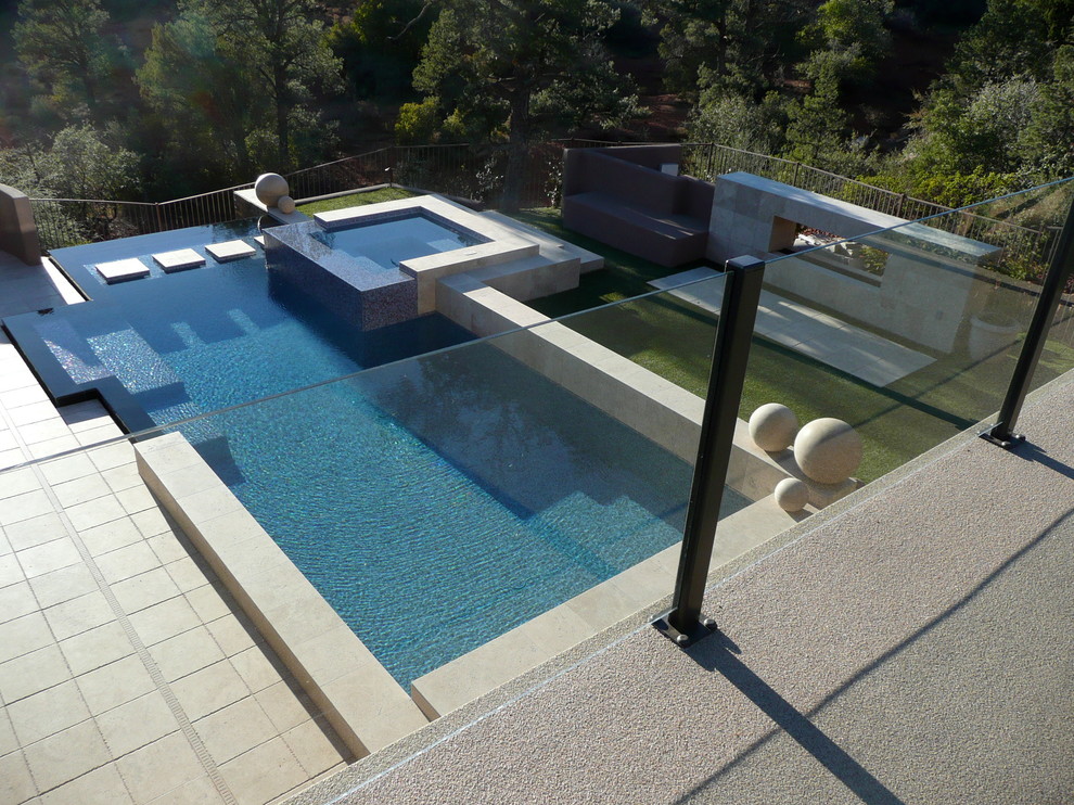 Foto di una piscina a sfioro infinito moderna personalizzata dietro casa e di medie dimensioni con fontane e pedane