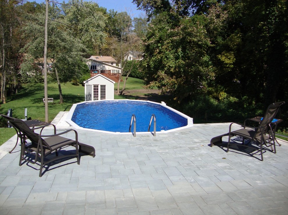 Imagen de piscina elevada tradicional de tamaño medio a medida en patio trasero con adoquines de hormigón