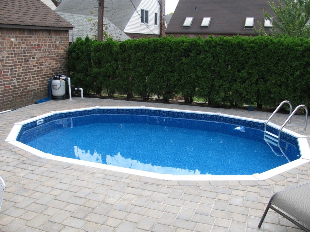 Exempel på en mellanstor klassisk rund pool på baksidan av huset, med kakelplattor