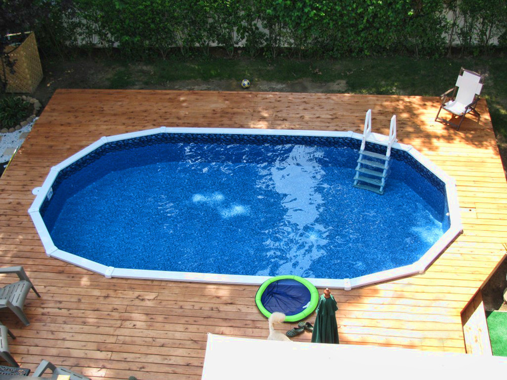 Example of a mid-sized classic backyard round aboveground pool design in New York with decking
