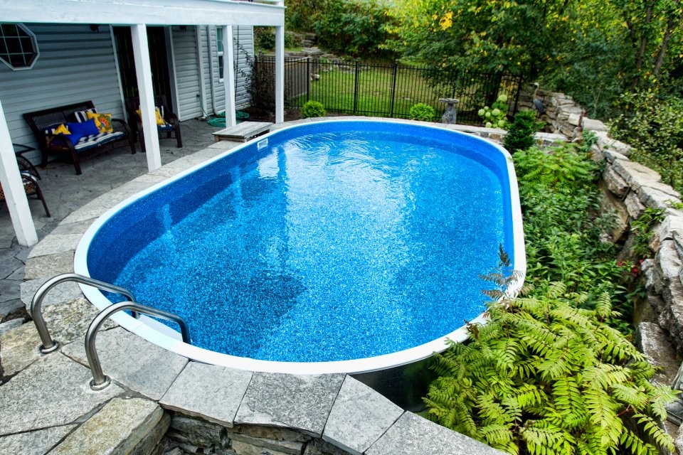 Immagine di una piscina fuori terra chic rotonda di medie dimensioni e dietro casa con pavimentazioni in pietra naturale