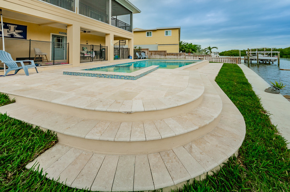 Ispirazione per una piscina a sfioro infinito costiera personalizzata di medie dimensioni e dietro casa con una vasca idromassaggio e pedane