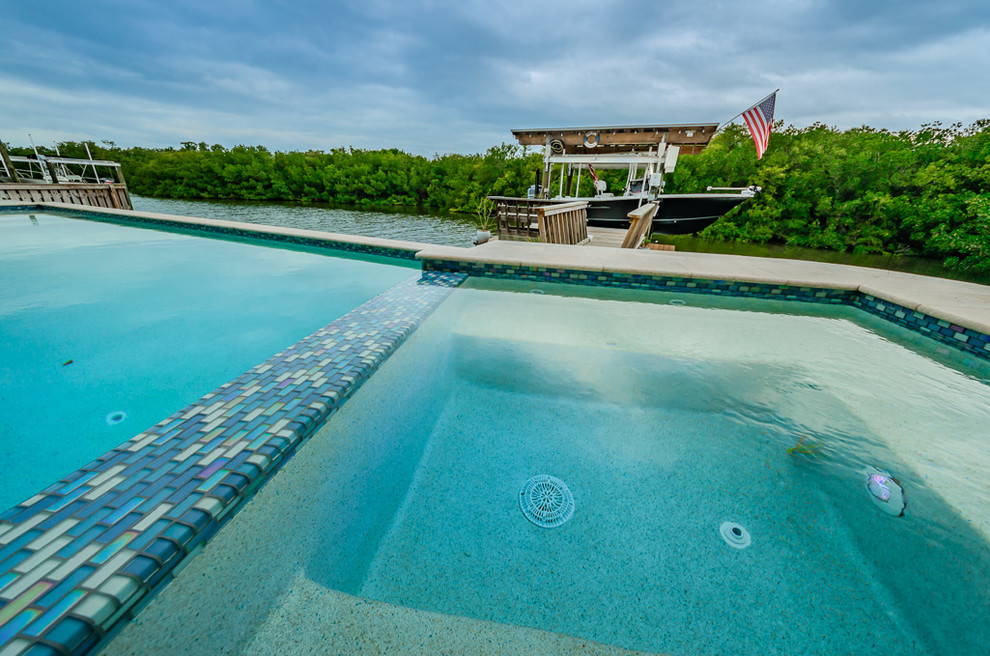 Foto di una piscina a sfioro infinito costiera personalizzata di medie dimensioni e dietro casa con una vasca idromassaggio e pedane