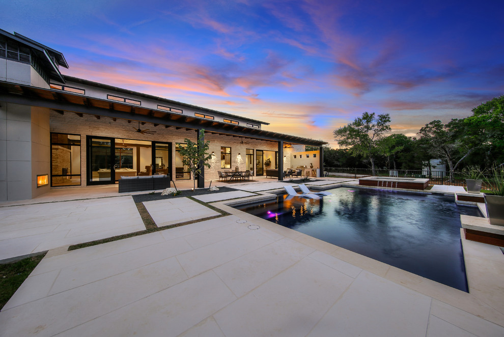 Ejemplo de casa de la piscina y piscina natural tradicional renovada grande rectangular en patio trasero con adoquines de piedra natural