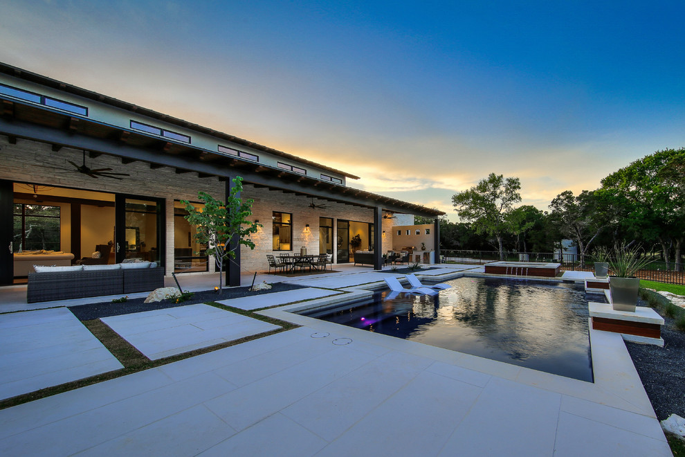 Идея дизайна: большой естественный, прямоугольный бассейн на заднем дворе в стиле неоклассика (современная классика) с домиком у бассейна и покрытием из каменной брусчатки