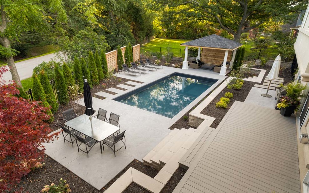 Immagine di una piscina monocorsia minimalista rettangolare di medie dimensioni e dietro casa con lastre di cemento