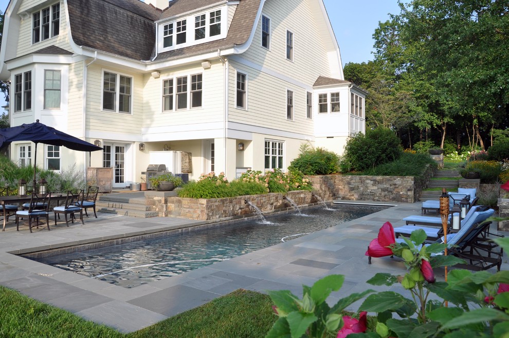 Diseño de piscina con fuente alargada de estilo americano extra grande rectangular en patio lateral con adoquines de piedra natural