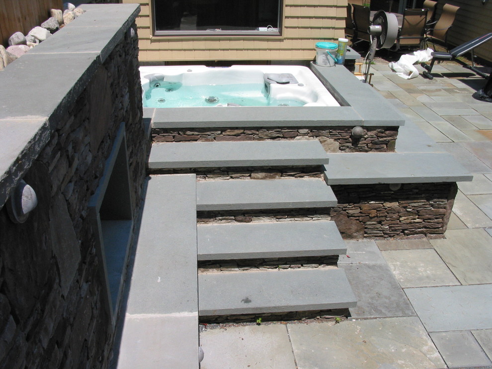 Foto di una piscina tradizionale di medie dimensioni e dietro casa con una vasca idromassaggio e pavimentazioni in pietra naturale
