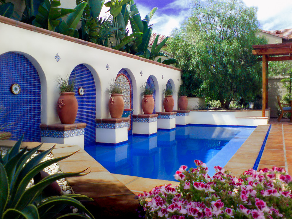 Example of a mid-sized tuscan backyard tile and rectangular pool design in Los Angeles