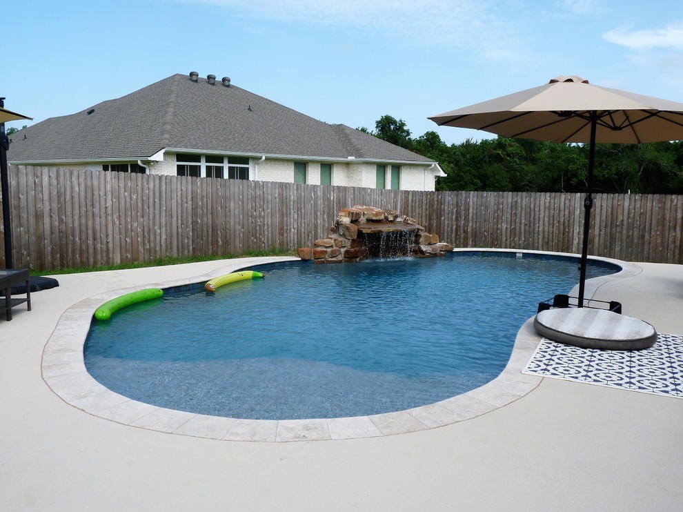 Foto di una piscina naturale tropicale a "C" di medie dimensioni e dietro casa con fontane e pedane