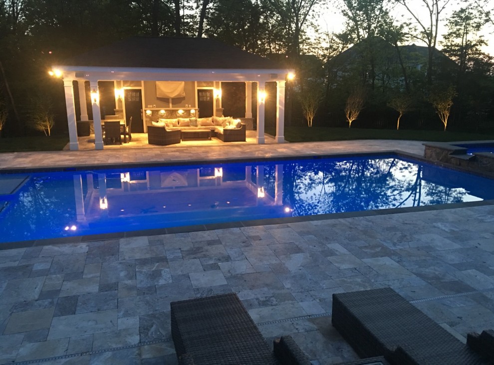 Ejemplo de piscina con fuente alargada actual grande rectangular en patio trasero con adoquines de piedra natural