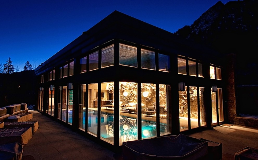 Diseño de casa de la piscina y piscina actual grande rectangular y interior con adoquines de hormigón