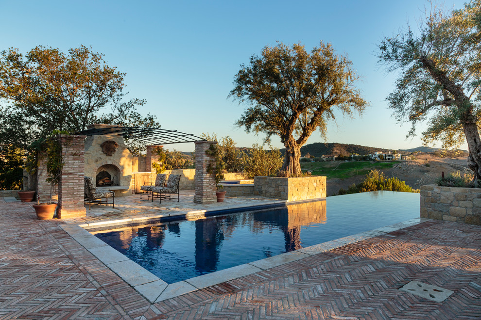 Idee per una grande piscina a sfioro infinito mediterranea rettangolare dietro casa con pavimentazioni in mattoni e una vasca idromassaggio