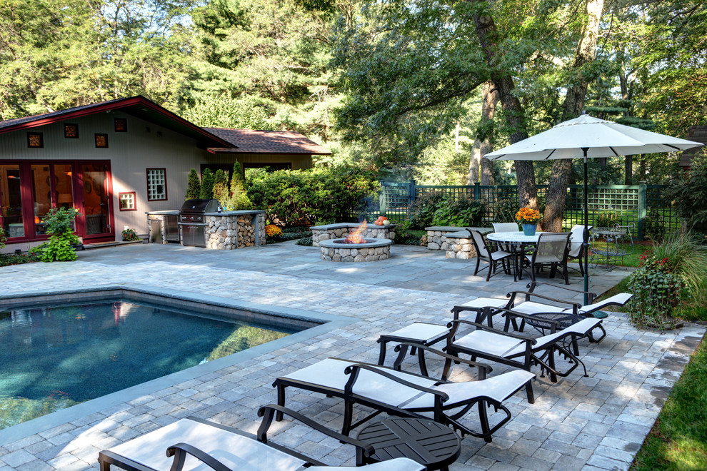 This is an example of a large rustic back custom shaped lengths swimming pool in Boston with natural stone paving.