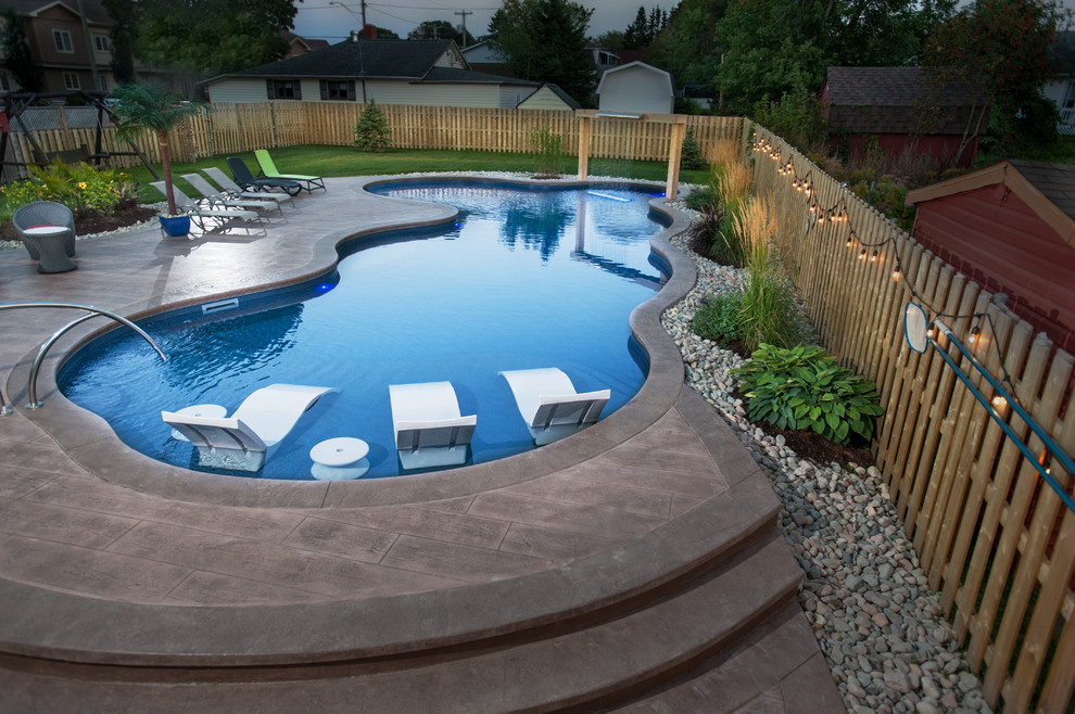 Pool house - large coastal side yard stamped concrete and custom-shaped natural pool house idea in Other