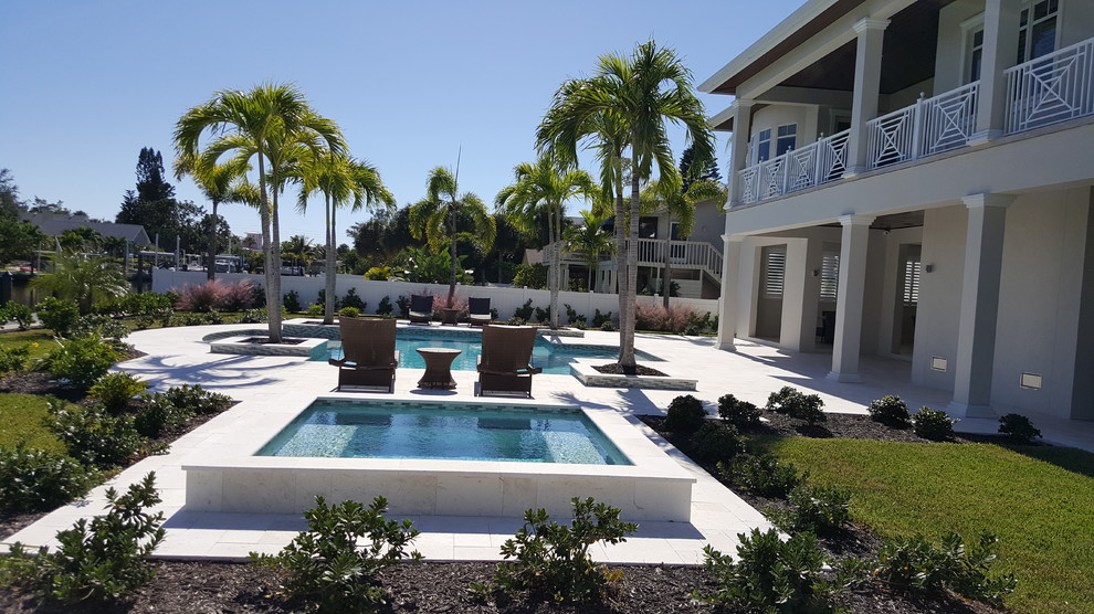 Inspiration for a large contemporary back custom shaped natural swimming pool in Miami with a pool house and natural stone paving.
