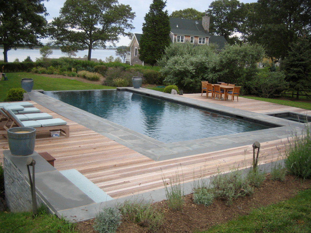 Inspiration for a large eclectic backyard rectangular infinity hot tub remodel in New York with decking