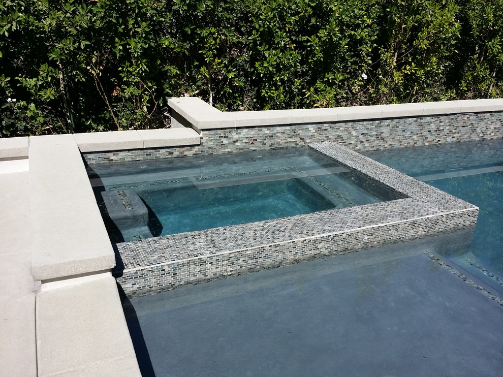 Aménagement d'une piscine arrière moderne de taille moyenne et rectangle avec un point d'eau et des pavés en béton.