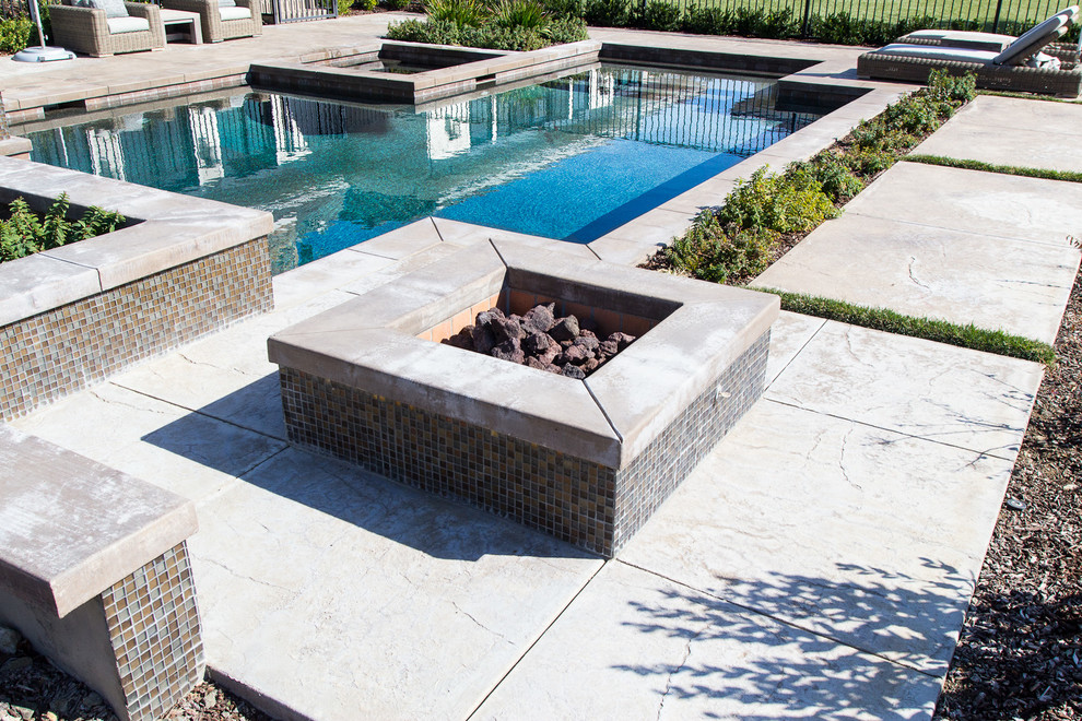 Diseño de piscinas y jacuzzis contemporáneos de tamaño medio en forma de L en patio trasero con adoquines de hormigón