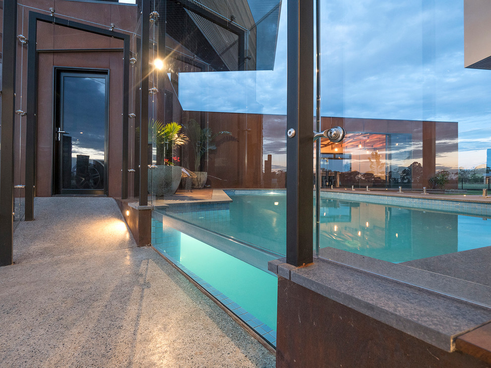 Moderner Pool hinter dem Haus in rechteckiger Form mit Dielen in Sonstige