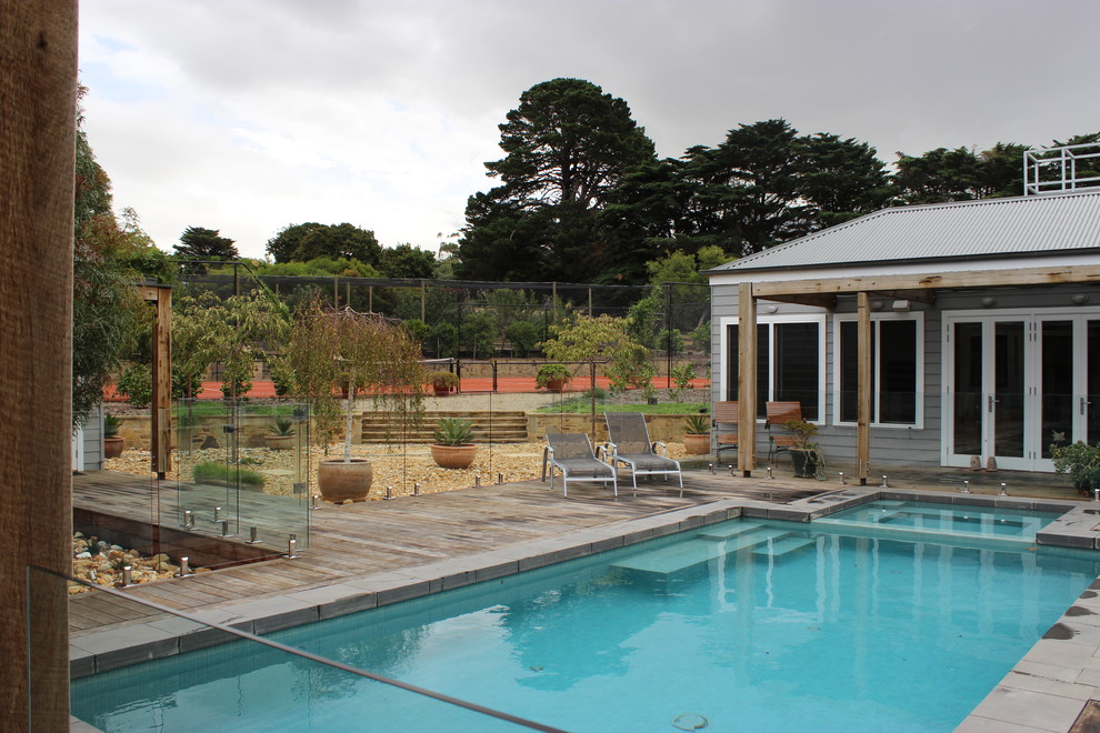 Exemple d'une grande piscine naturelle éclectique rectangle avec une cour, une terrasse en bois et un bain bouillonnant.