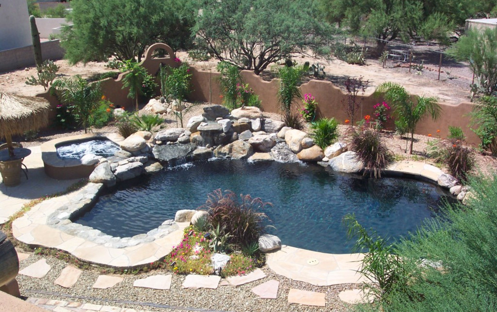 Idee per una grande piscina tropicale personalizzata dietro casa con una vasca idromassaggio e pavimentazioni in cemento