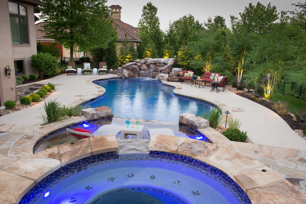 Modelo de piscinas y jacuzzis naturales rústicos redondeados en patio trasero con adoquines de piedra natural
