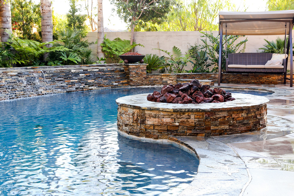 Immagine di una piscina monocorsia tradizionale a "C" di medie dimensioni e dietro casa con fontane e lastre di cemento
