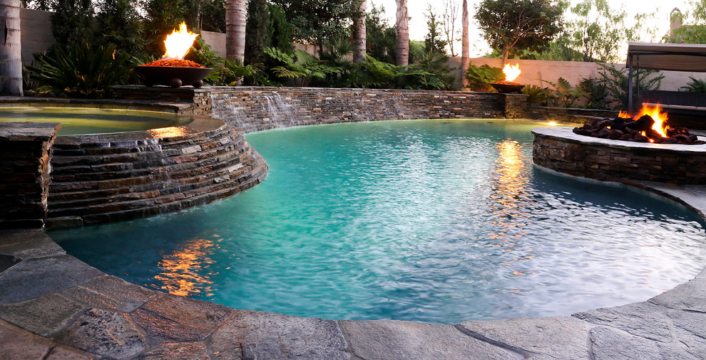 Imagen de piscina con fuente alargada tradicional de tamaño medio tipo riñón en patio trasero con losas de hormigón