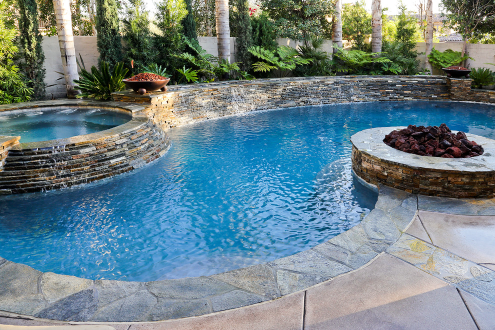 Foto di una piscina monocorsia classica a "C" di medie dimensioni e dietro casa con una vasca idromassaggio e lastre di cemento